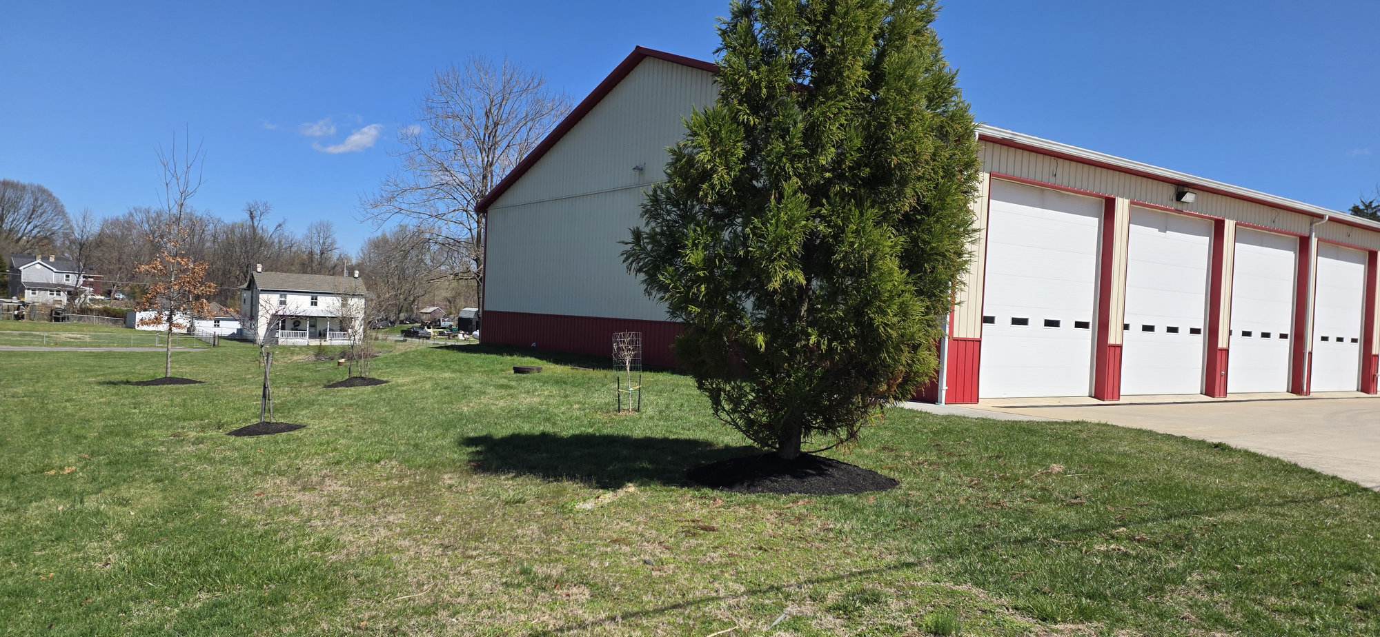 Bakerton Fire Department station and grounds with young trees newly planted in the lawn in early spring